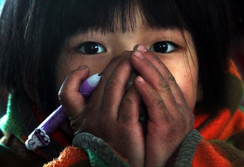 A girl warms her numb hands in the freezing classroom at the Fenghua Hope School in Haidian district, Beijing, January 7, 2010. Nearly 500 students took their exams earlier than in previous years due to the lack of fuel to heat the school. [Photo/CFP]